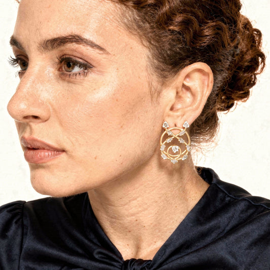 Close-up of a woman wearing gold hoop earrings with intricate designs.