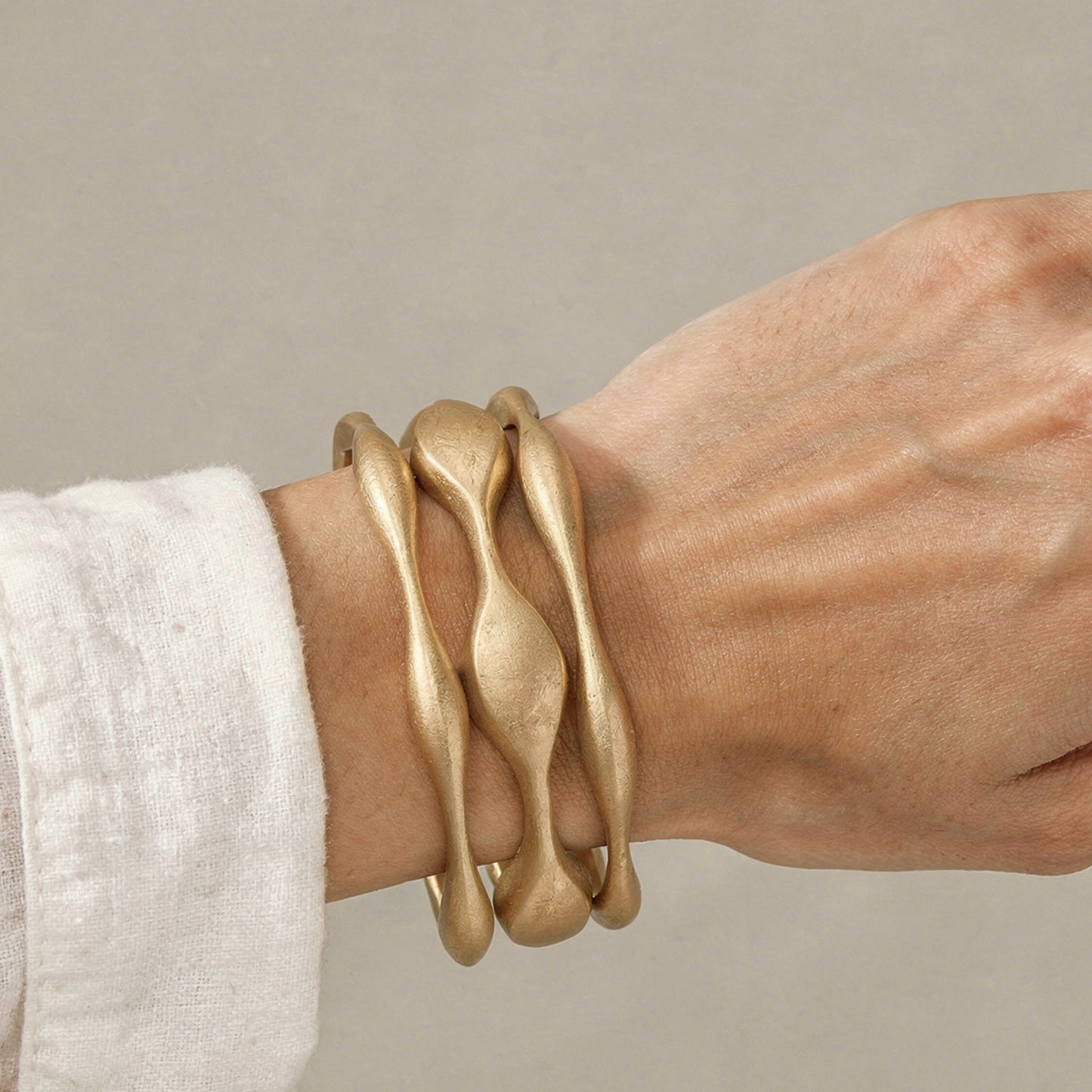 Gold bracelet on a wrist with a neutral background