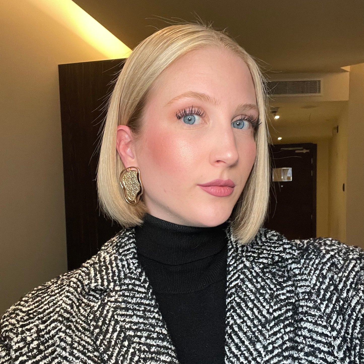 Close-up of a model wearing abstract gold contour earrings from the Contour Collection.