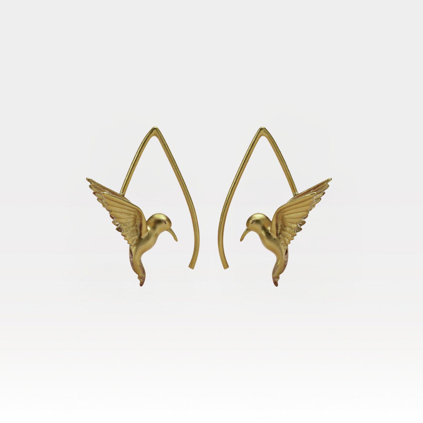 Gold hummingbird earrings on a light gray background