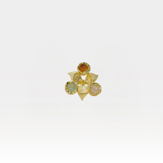 Gold flower-shaped ring with gemstones on a white background