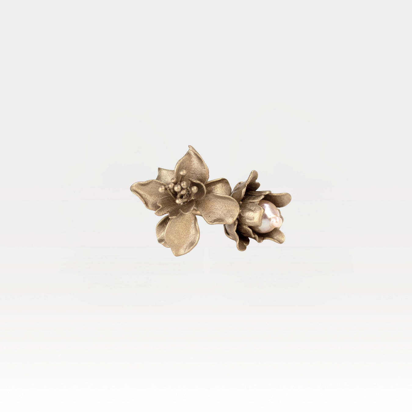 Pair of gold floral ring on a light gray background