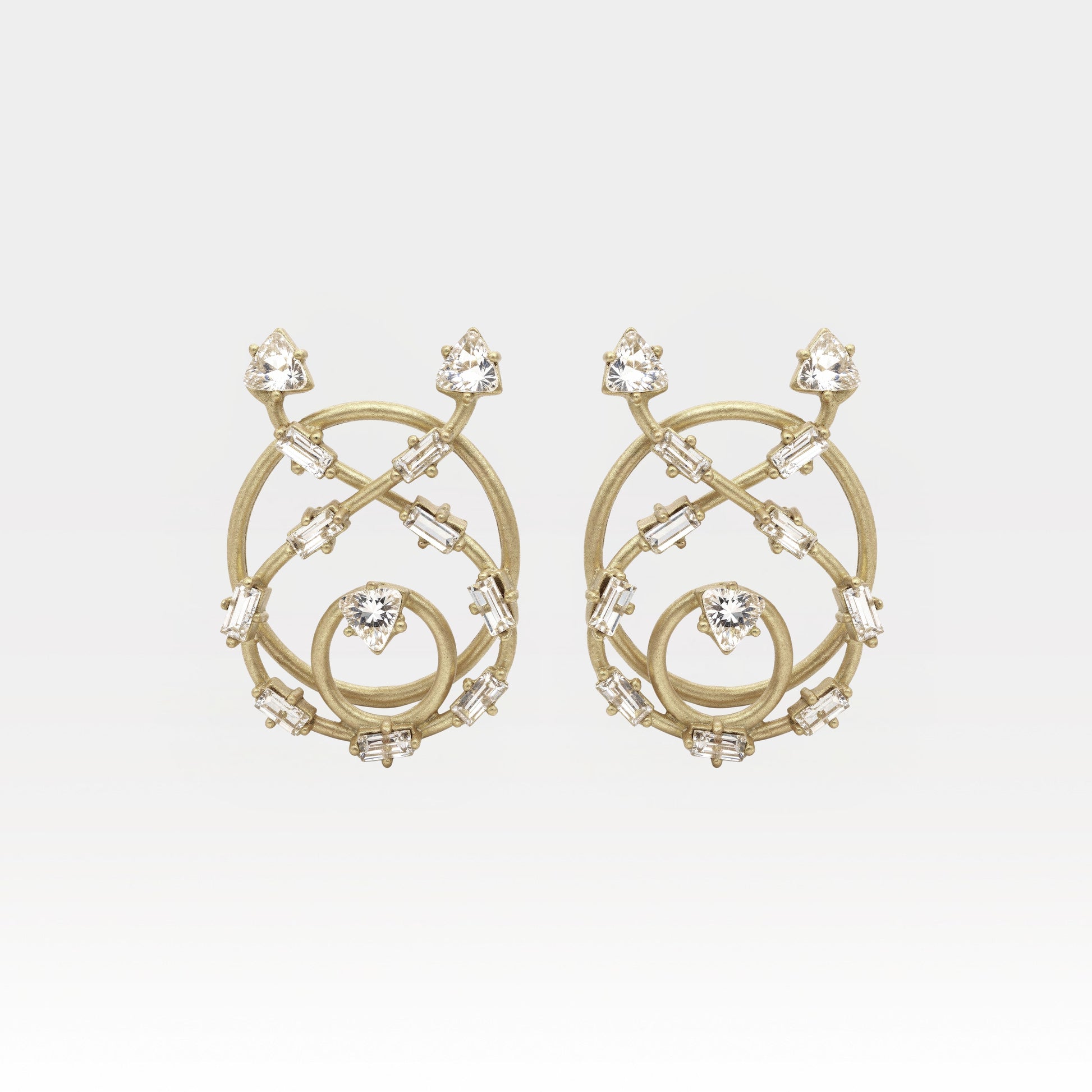 Gold earrings with intricate design and clear stones on a light gray background