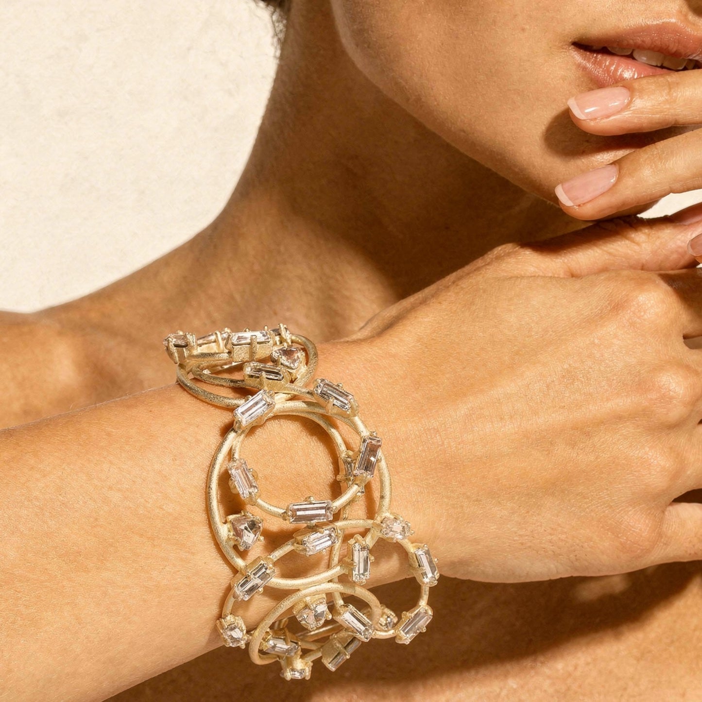 Gold bracelet with clear stones on a wrist, close-up of hand and arm.