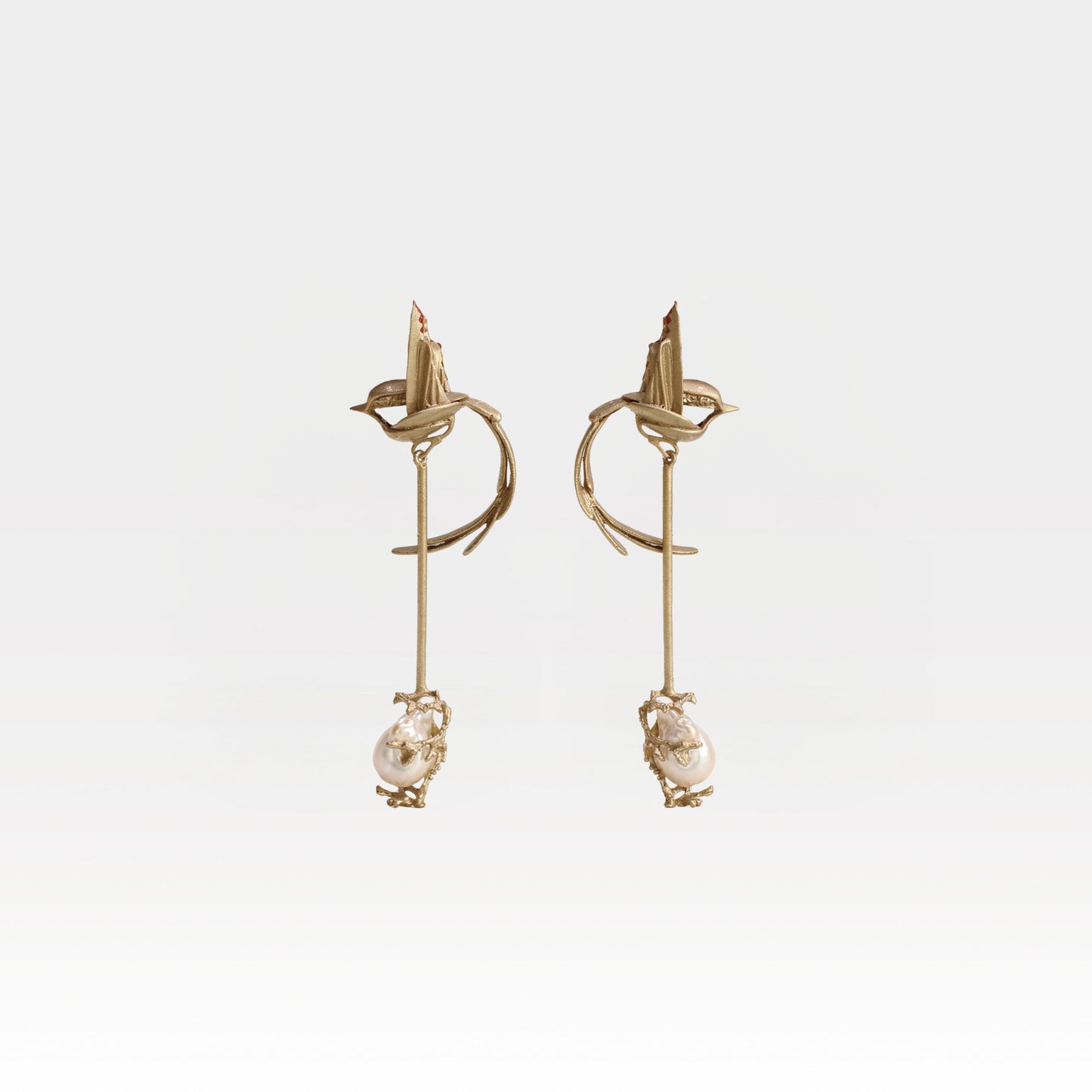 Gold earrings with pearl drops on a light gray background