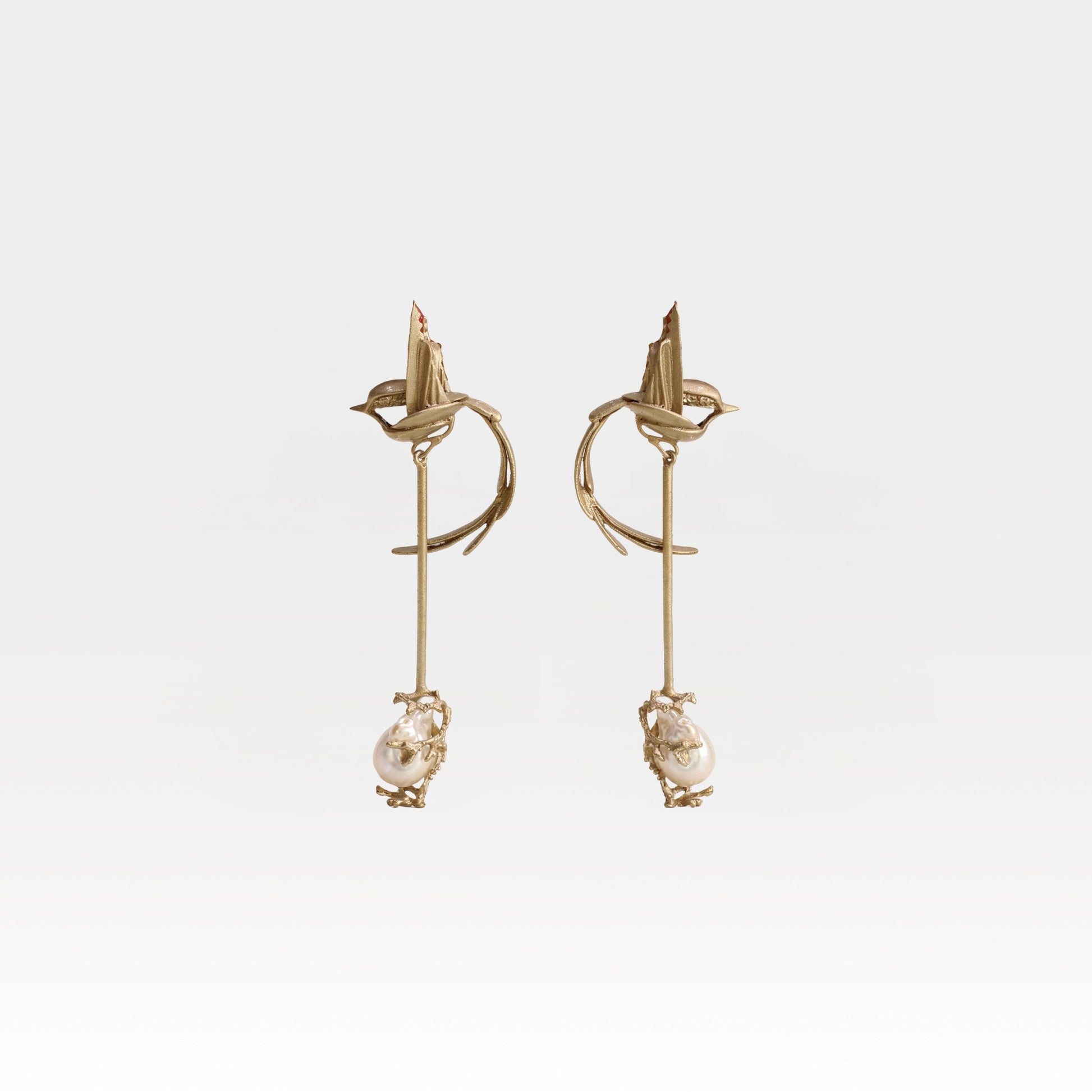 Gold earrings with pearl drops on a light gray background