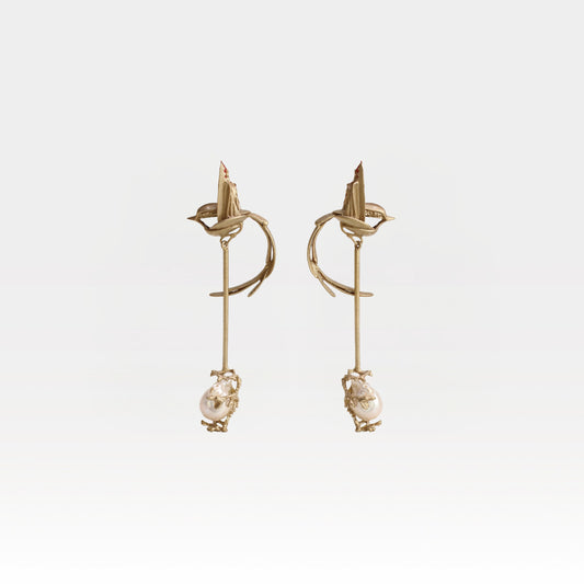 Gold earrings with pearl drops on a light gray background