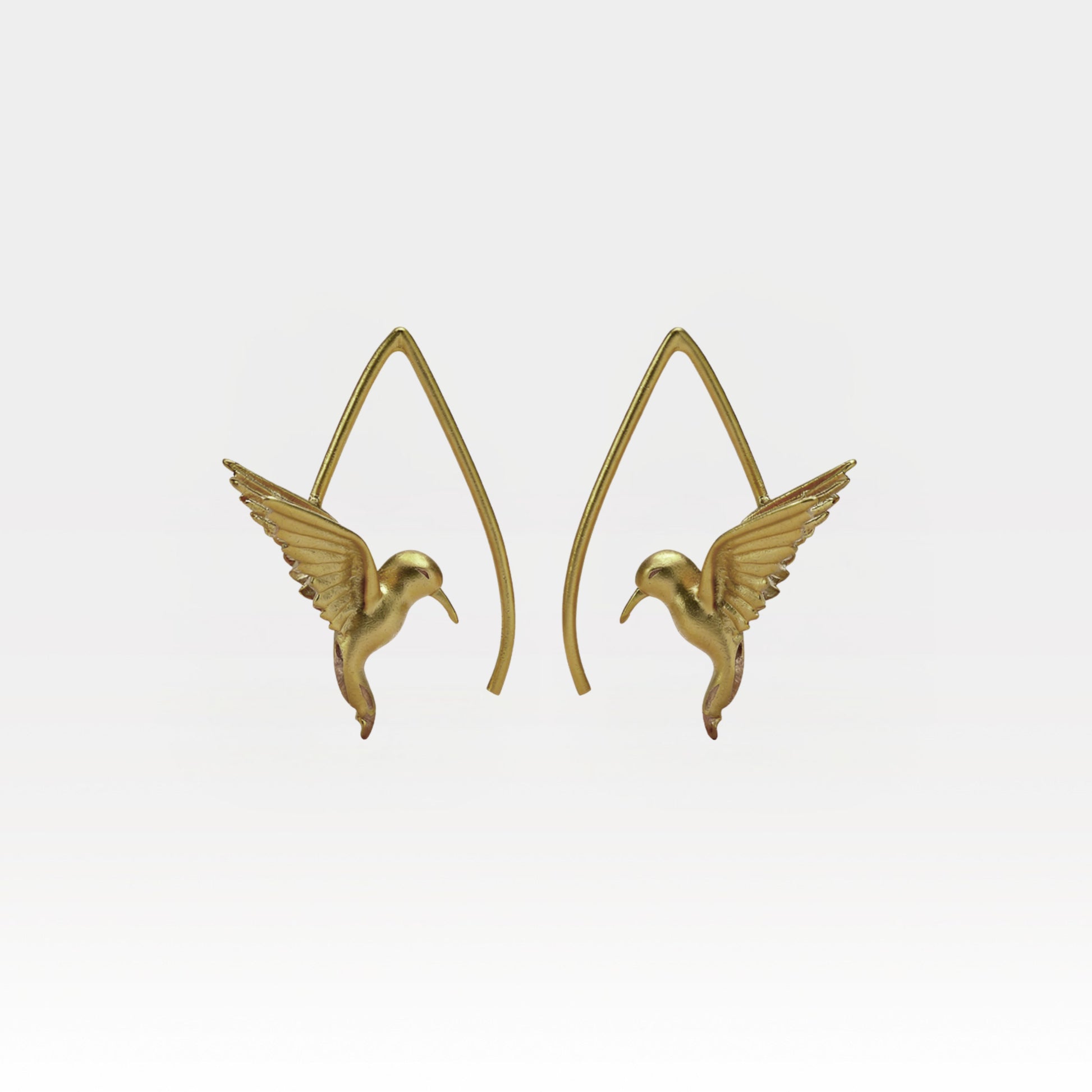 Gold hummingbird earrings on a light gray background