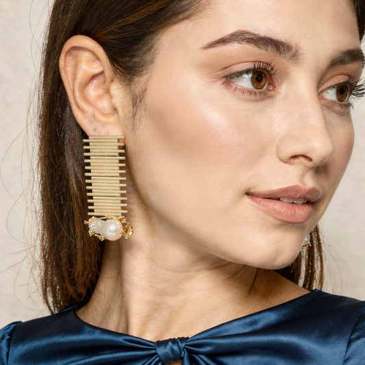 Close-up of a woman wearing gold earrings with a pearl accent.