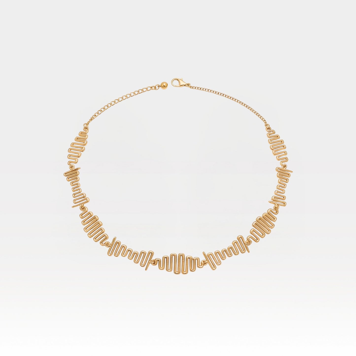 Gold necklace on a light gray background