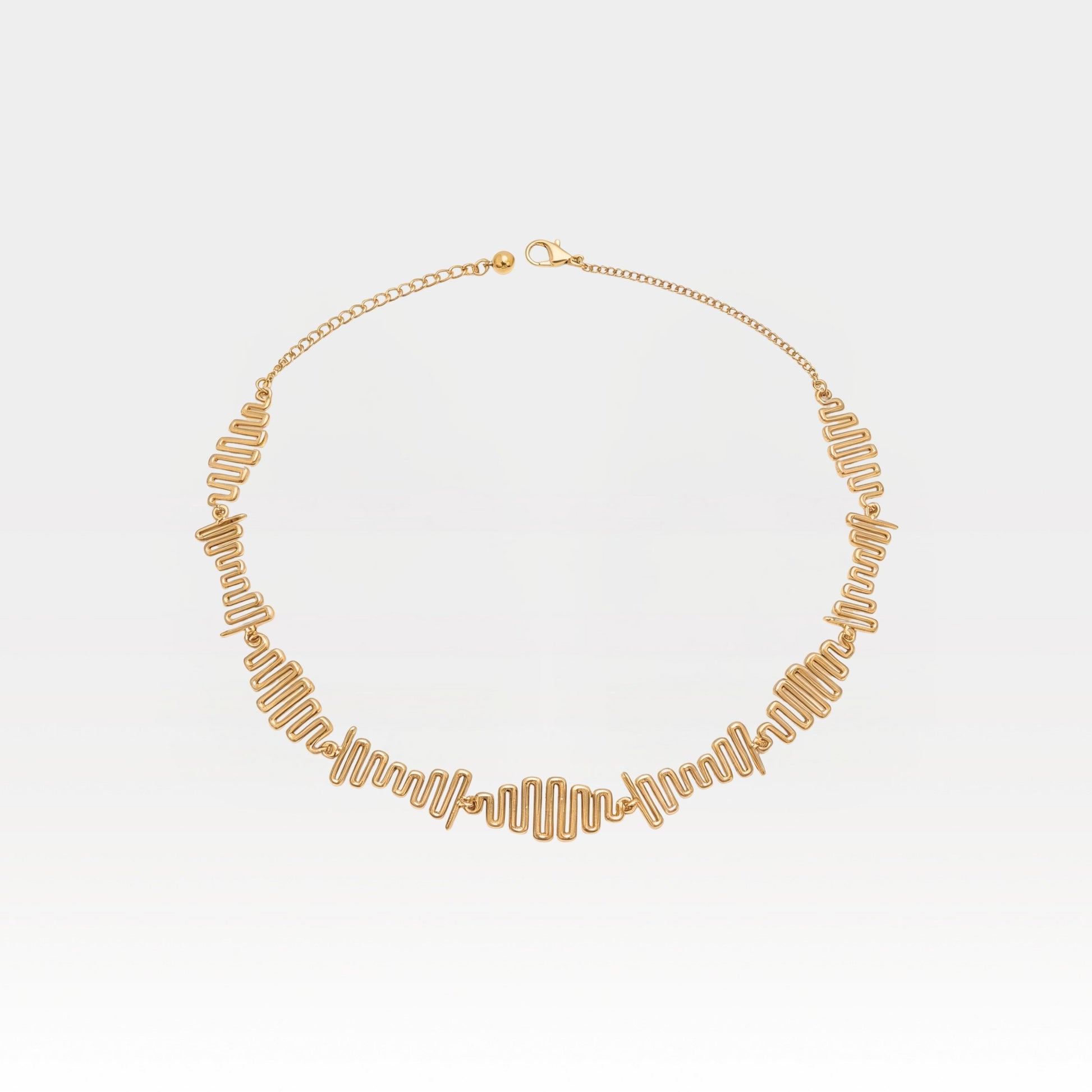 Gold necklace on a light gray background