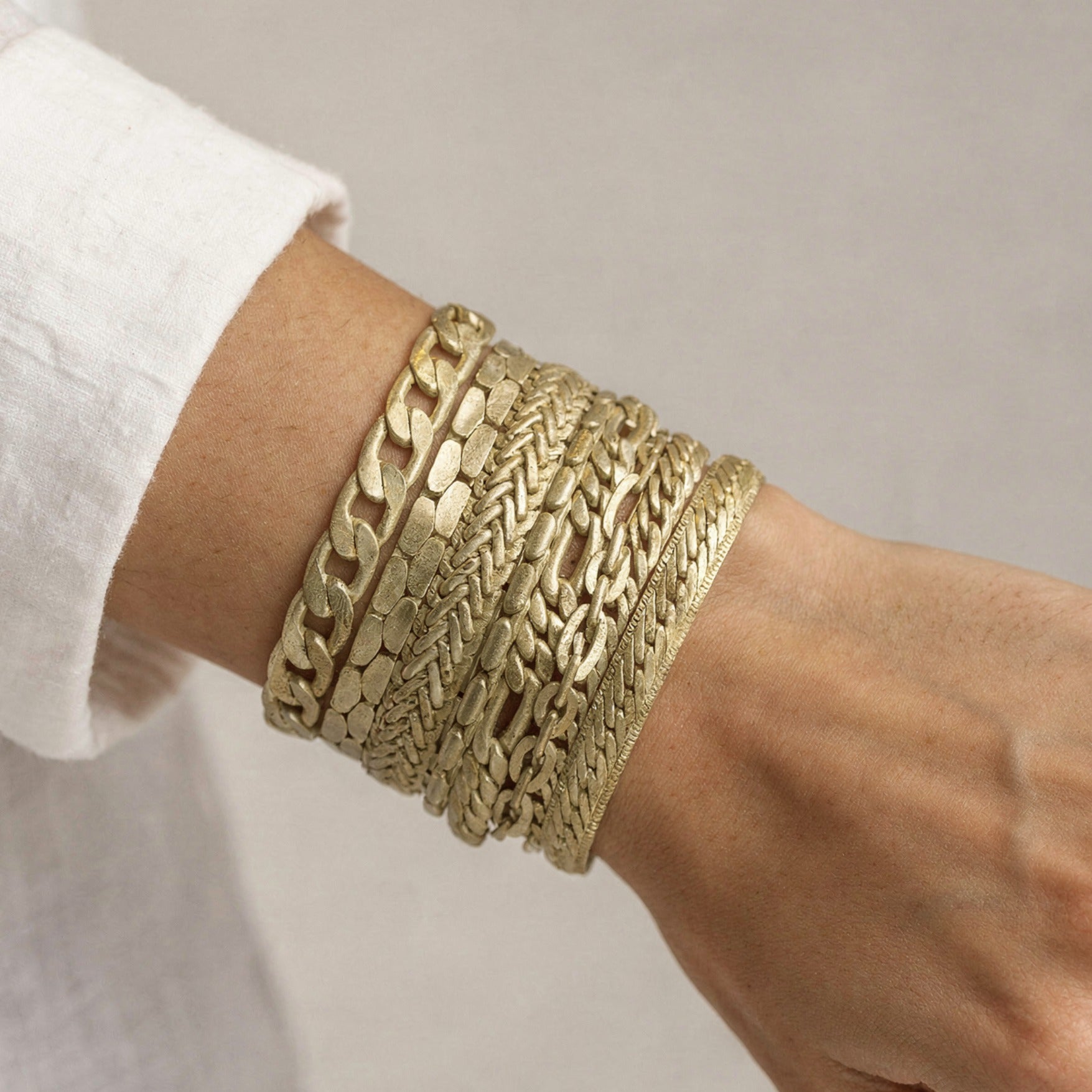 Gold chain bracelet on a wrist with a neutral background