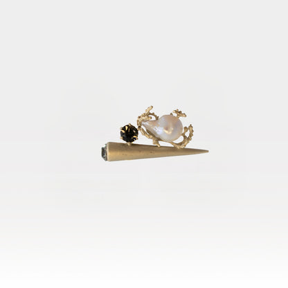 Gold cone-shaped ring with pearl and crystals on a white background
