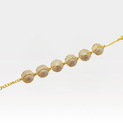 Kintsugi bracelet close-up showing textured gold spheres connected by chain, Japanese-inspired jewelry detail