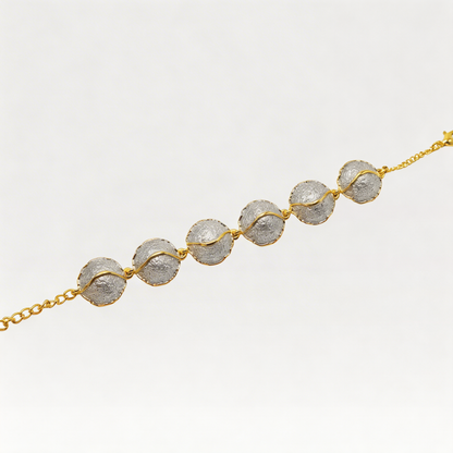 Bracelet with gold chain and metal domes on a light gray background