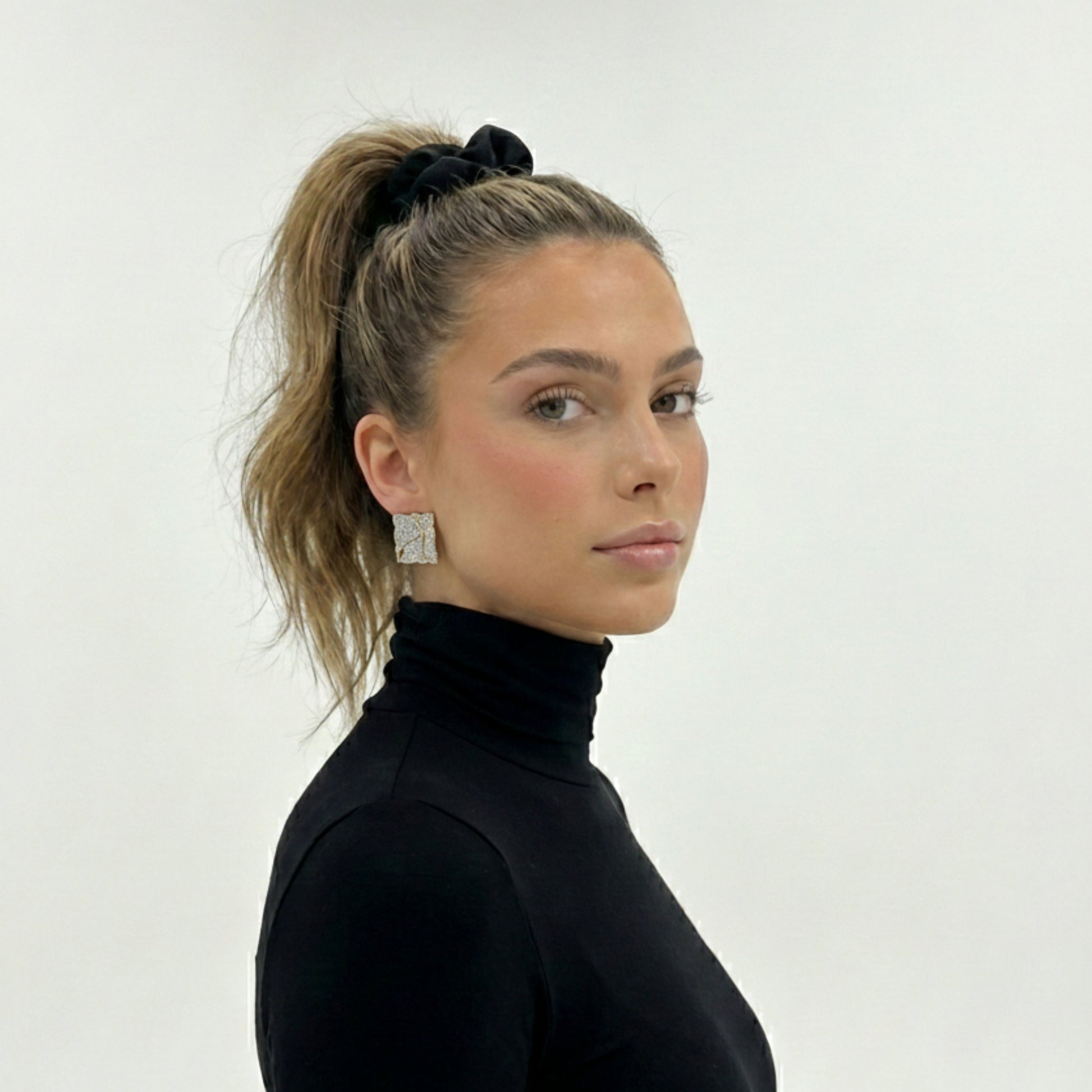 Woman wearing Kintsugi square stud earrings with gold and silver design, lifestyle jewelry photography
