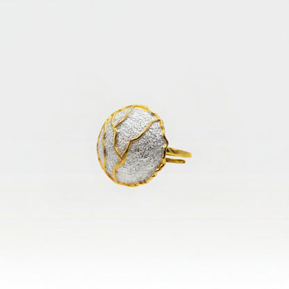 Kintsugi ring side view showing gold band and textured silver sphere with golden crack details