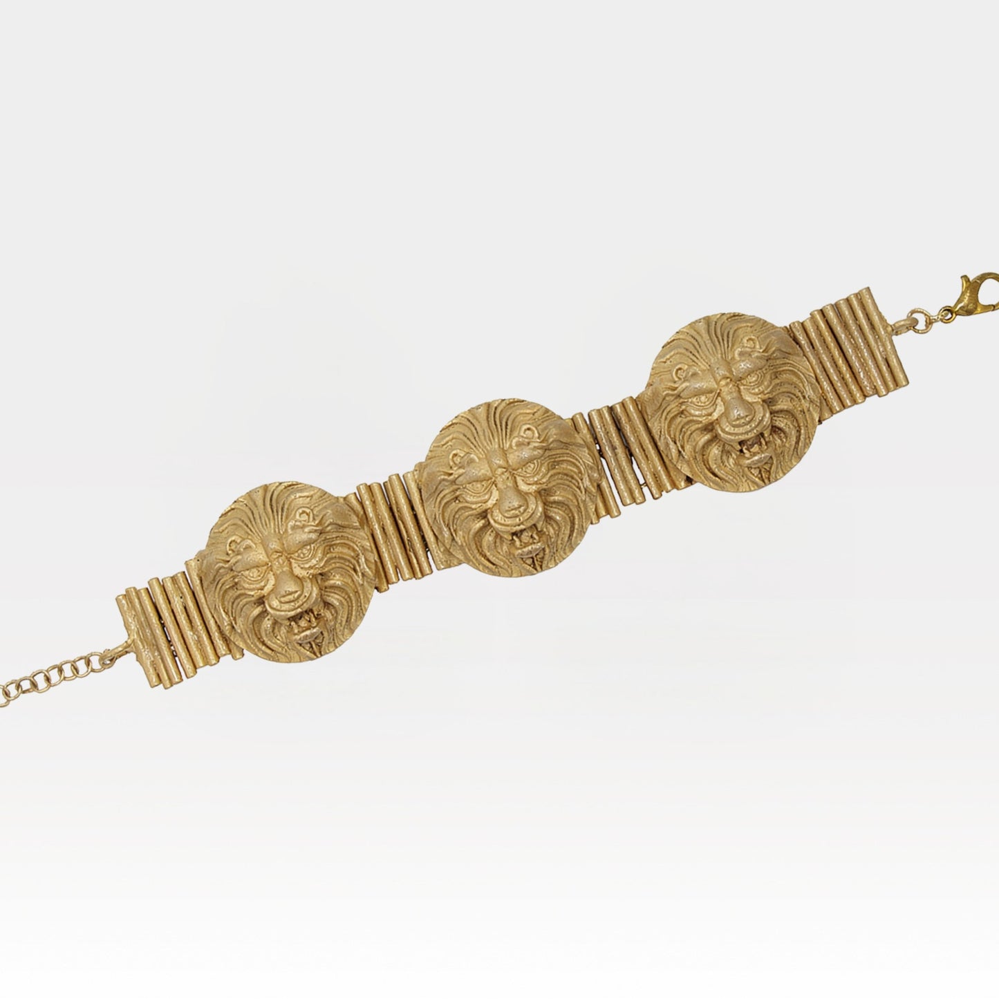 Gold bracelet with lion head designs on a white background