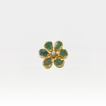 Gold flower-shaped ring with green gemstones on a white background