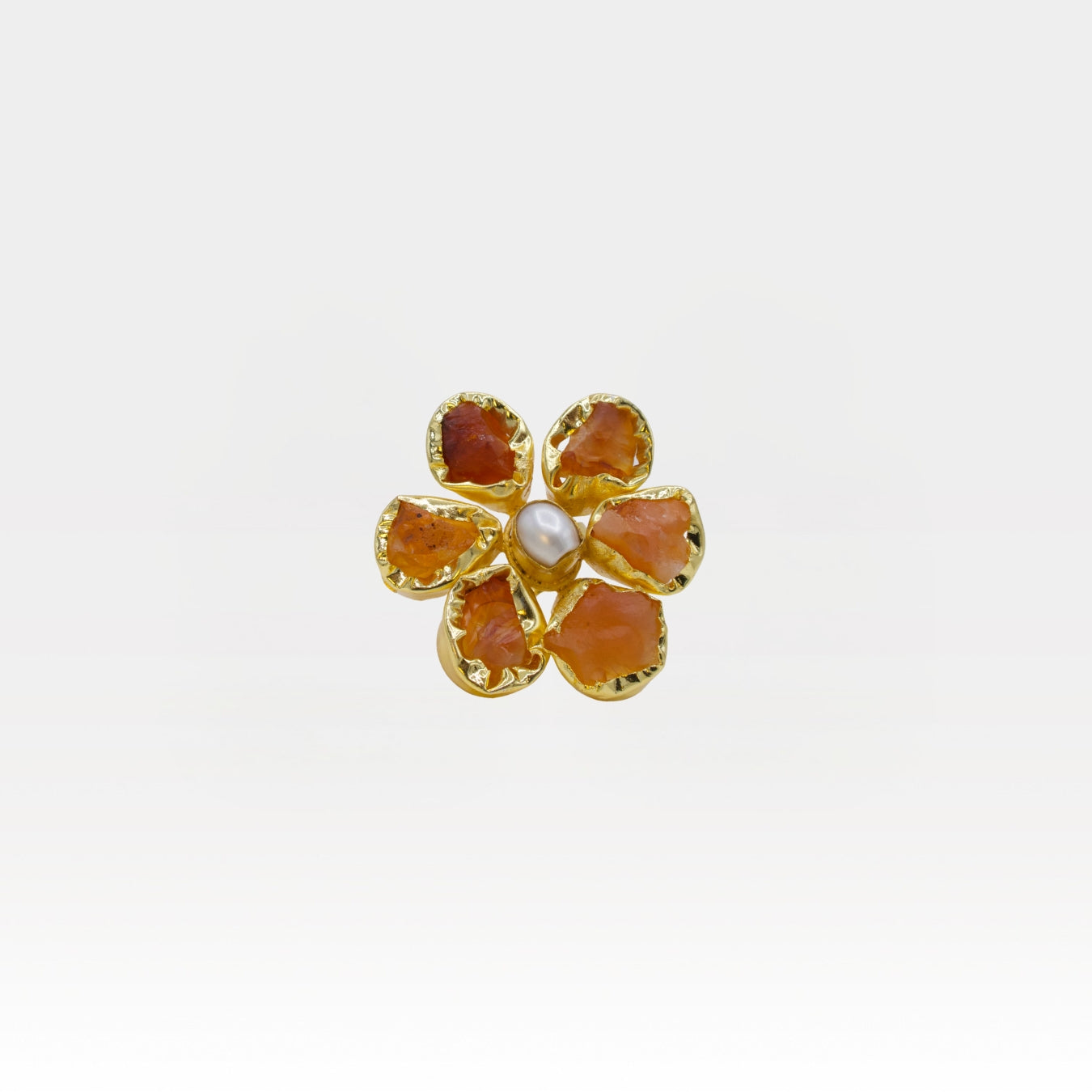 Gold flower-shaped ring with red stones on a white background