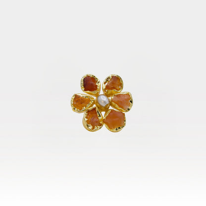 Gold flower-shaped ring with red stones on a white background