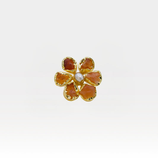 Gold flower-shaped ring with red stones on a white background