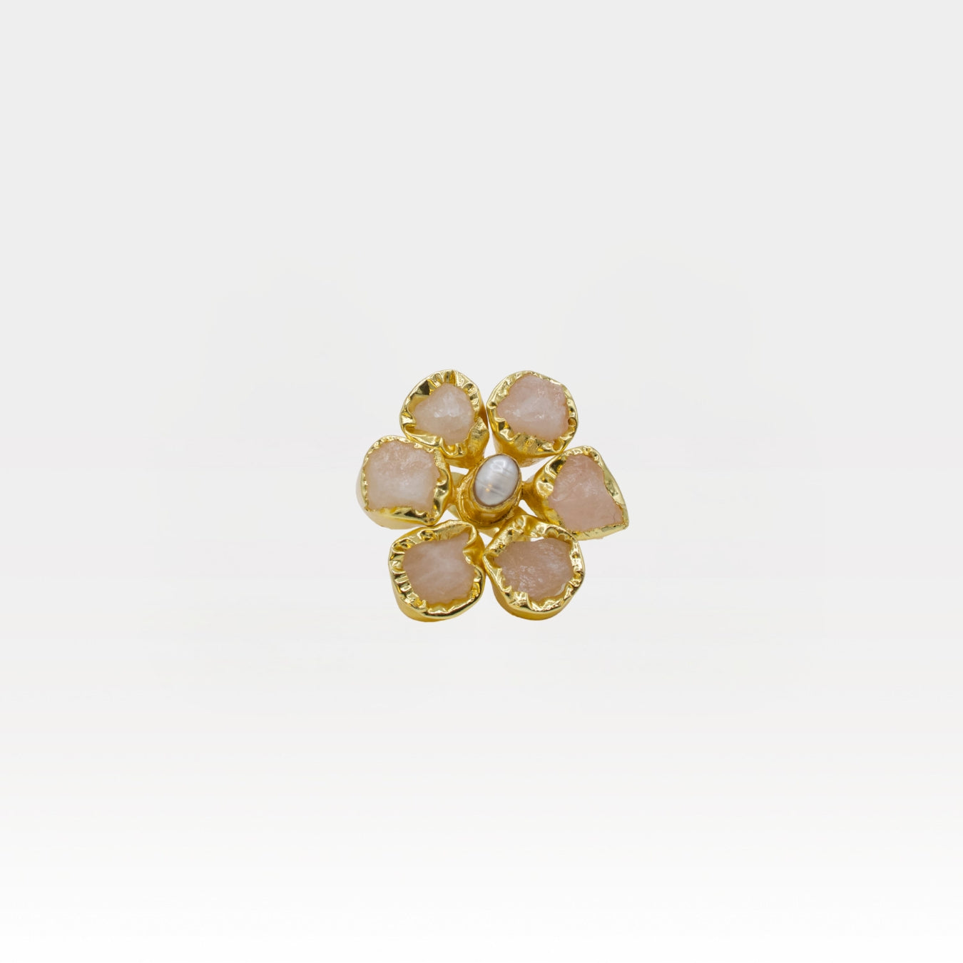 Gold flower-shaped ring with pink stones on a white background