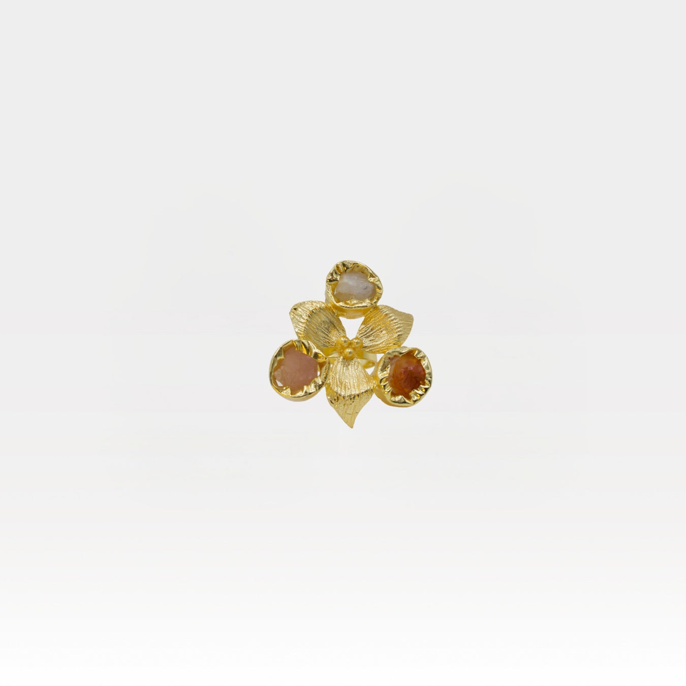 Gold ring with gemstones on a light gray background