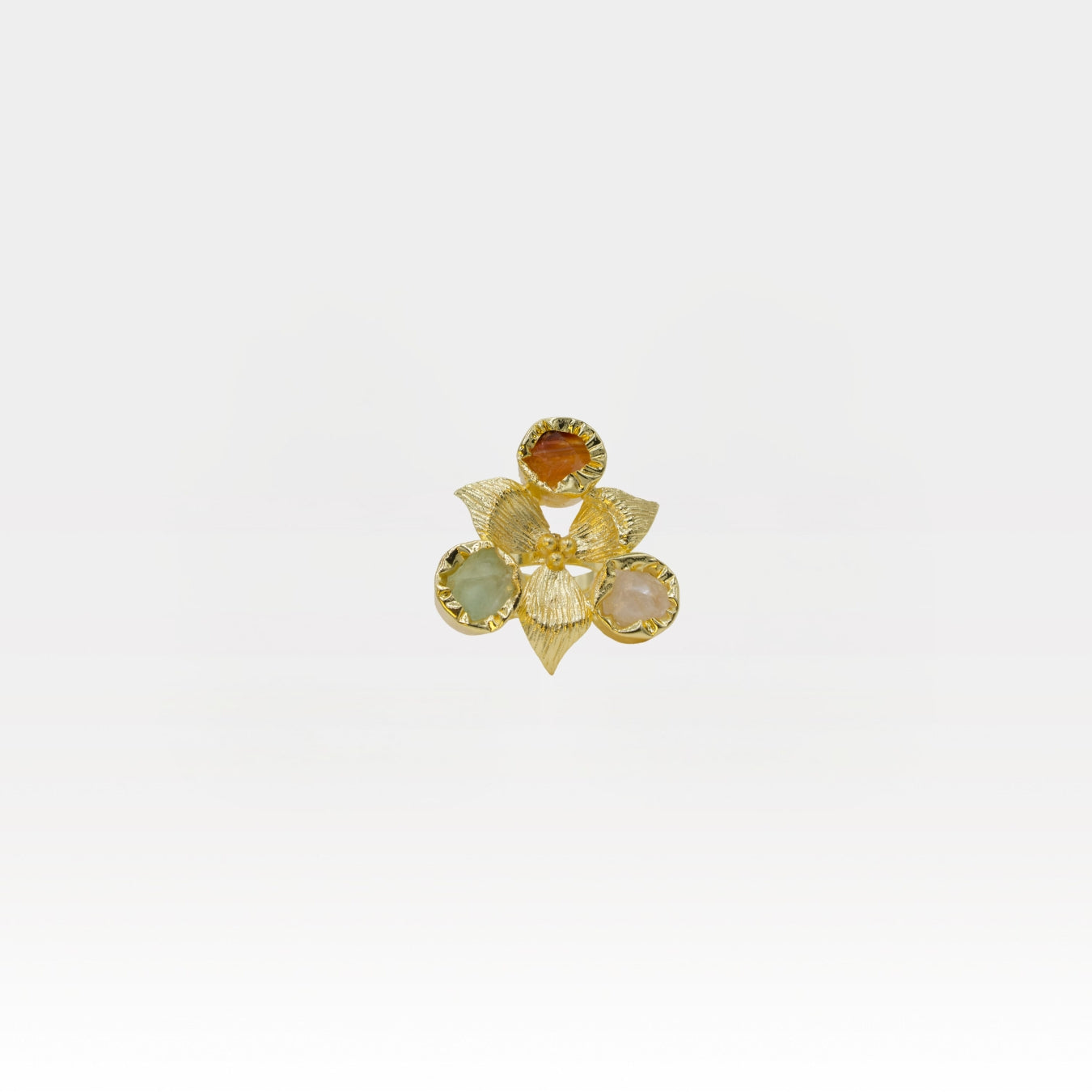 Gold flower-shaped ring with gemstones on a white background