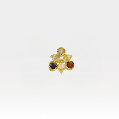 Gold flower-shaped ring with embedded gemstones on a white background