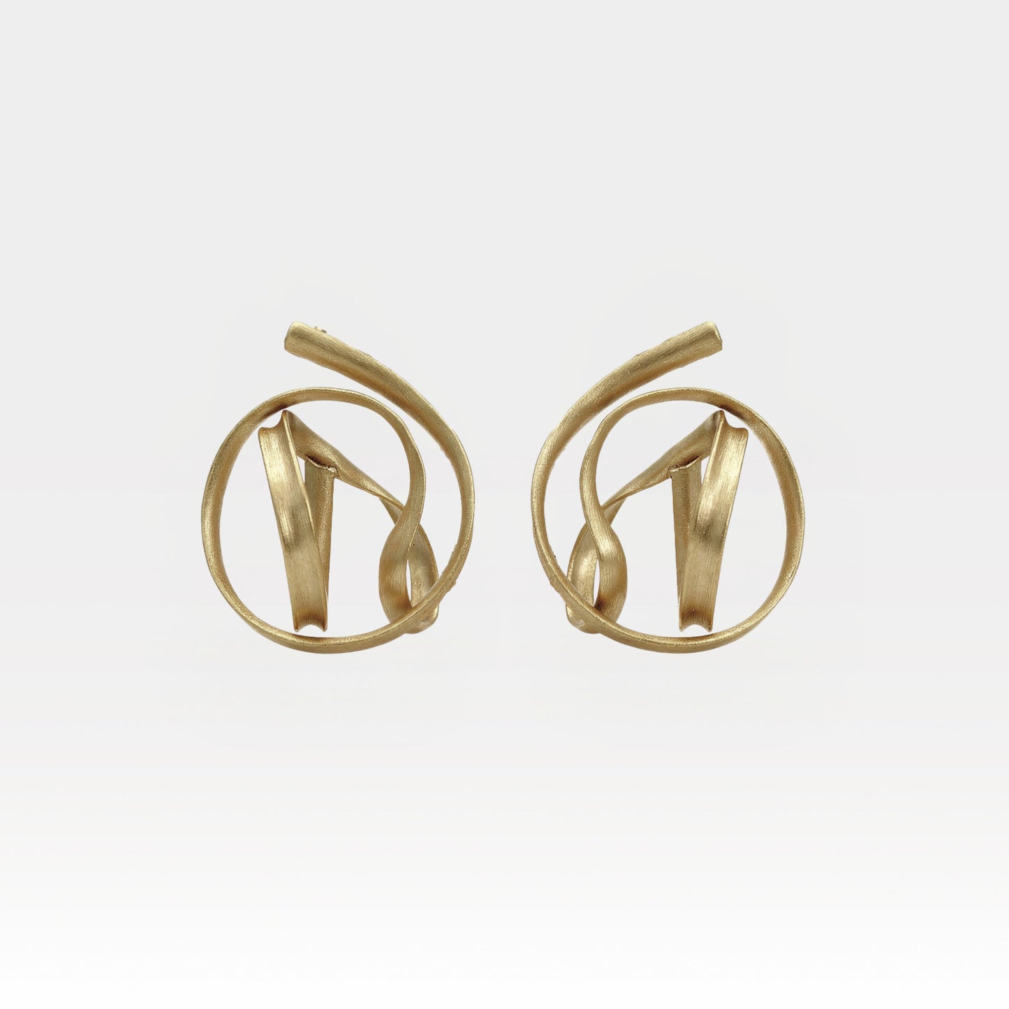 Pair of gold earrings on a light gray background