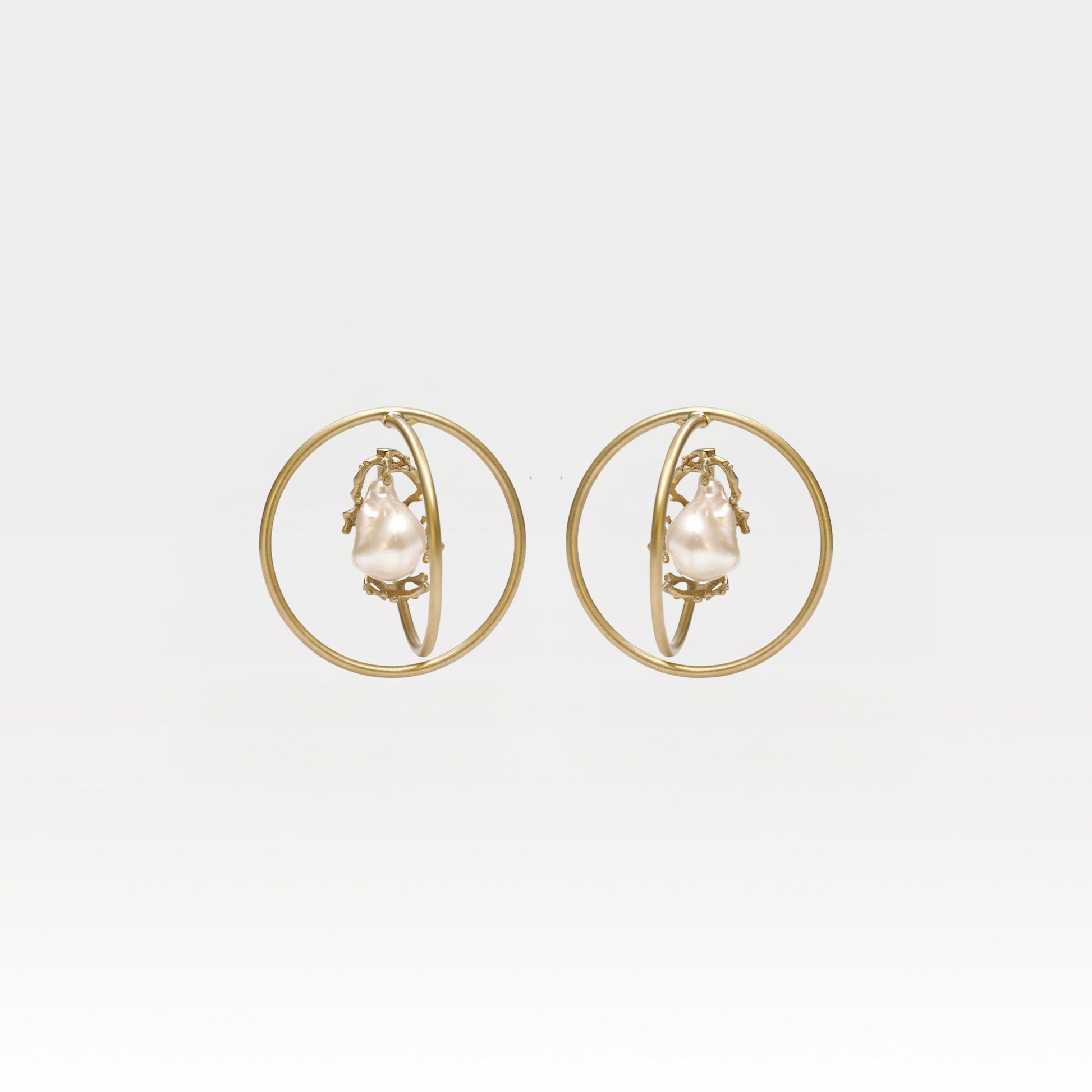 Gold hoop earrings with pearl center on a light gray background
