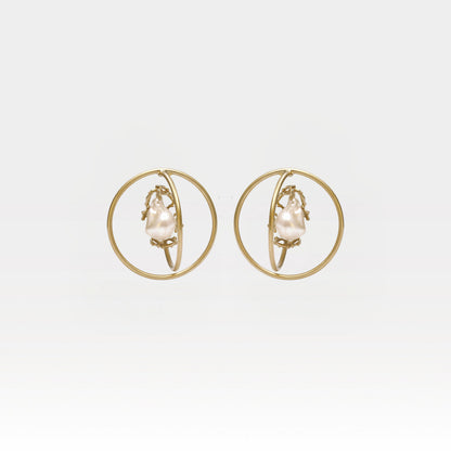 Gold hoop earrings with pearl center on a light gray background